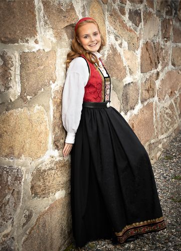 Young girl in traditional black dirndl dress poses against rustic stone wall in four sequential portrait shots.