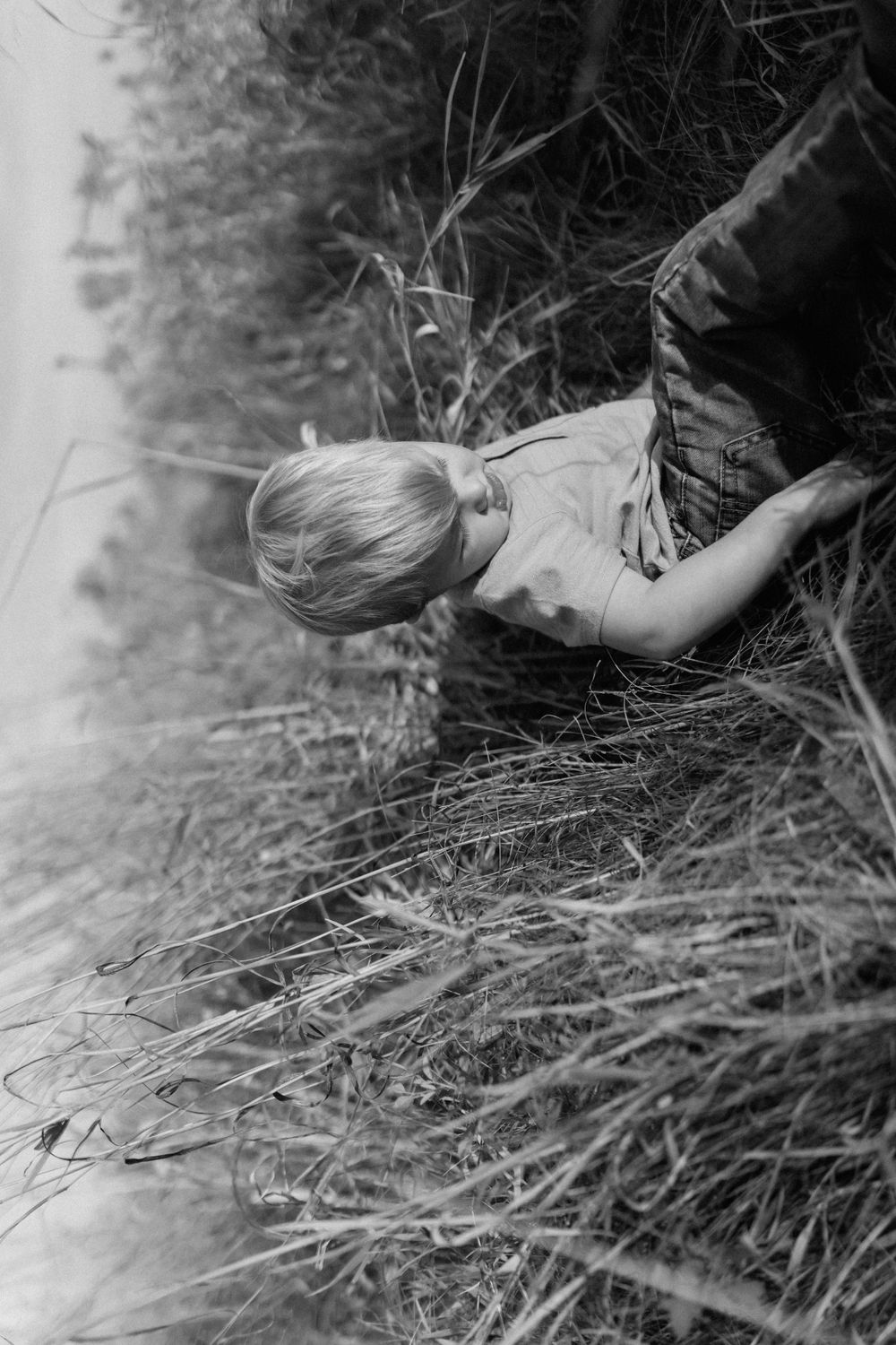 Child playing in tall grass in black and white photography.