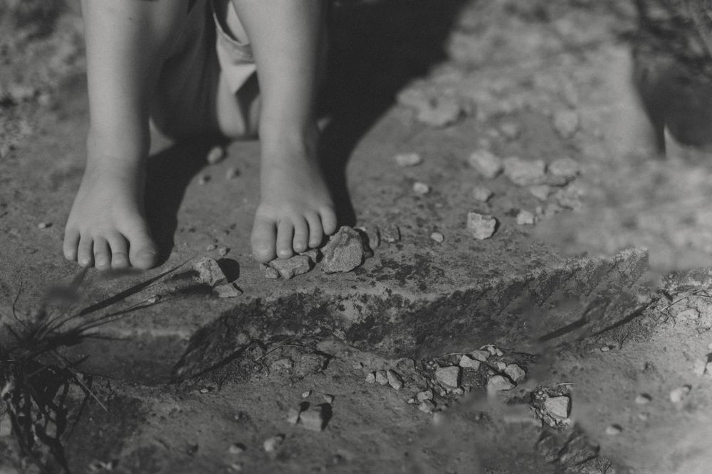 Black and white close-up of bare feet on a textured rocky surface.