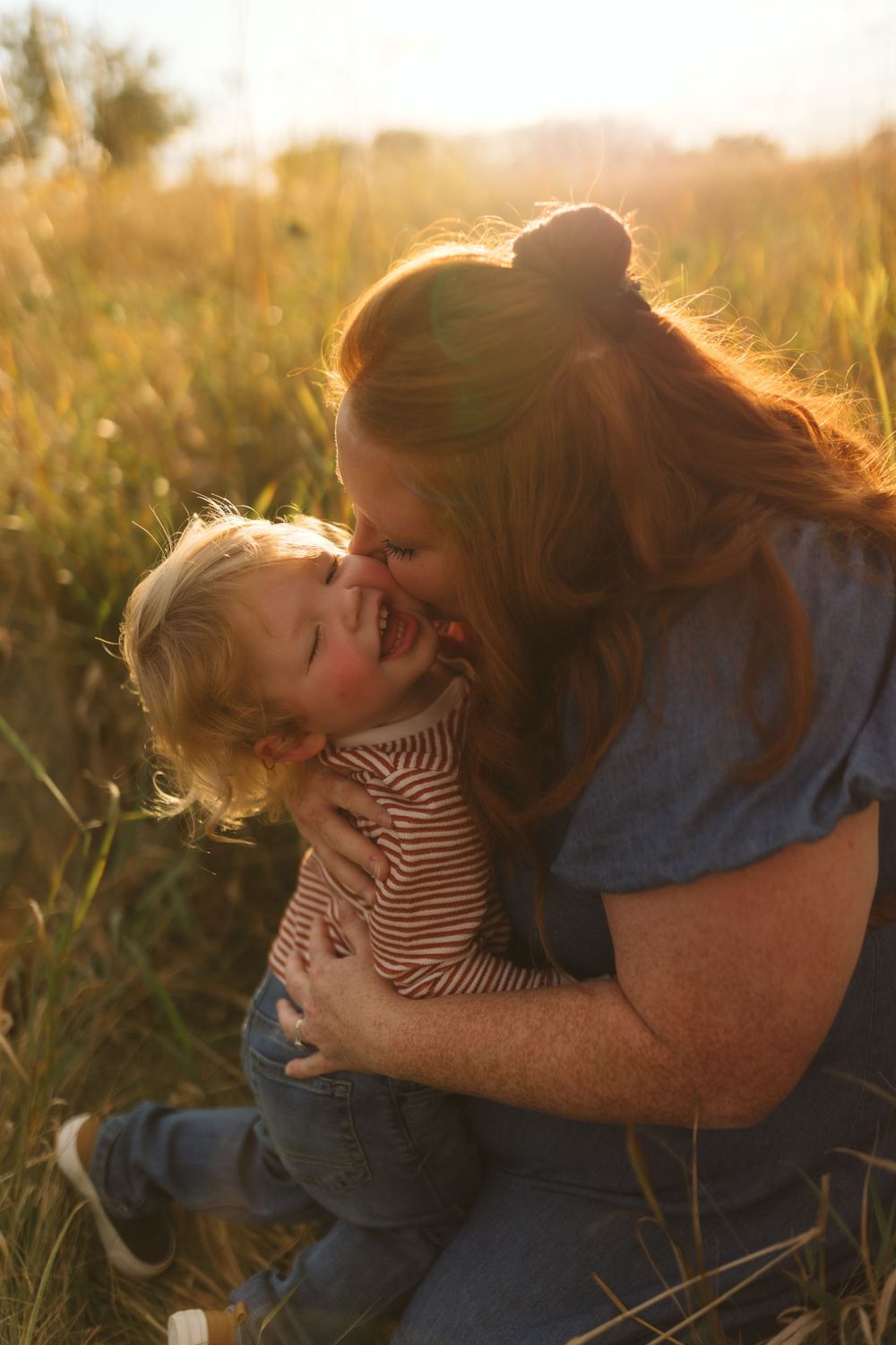 An intimate moment shared between two people in a sunlit field at golden hour.