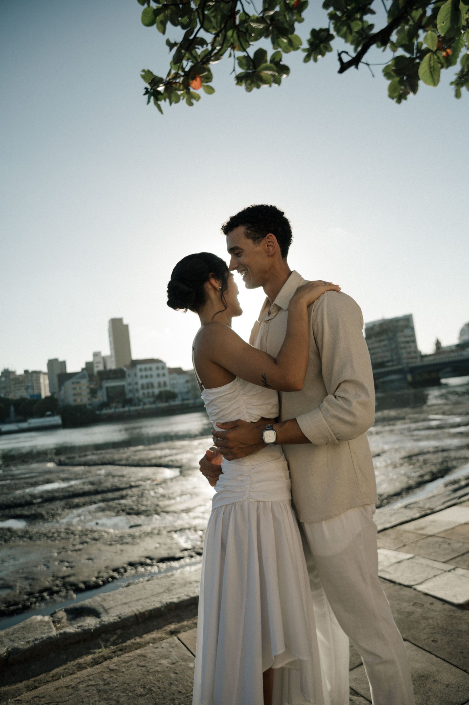 An intimate close-up portrait of a couple sharing a tender almost-kiss in warm sunlight.