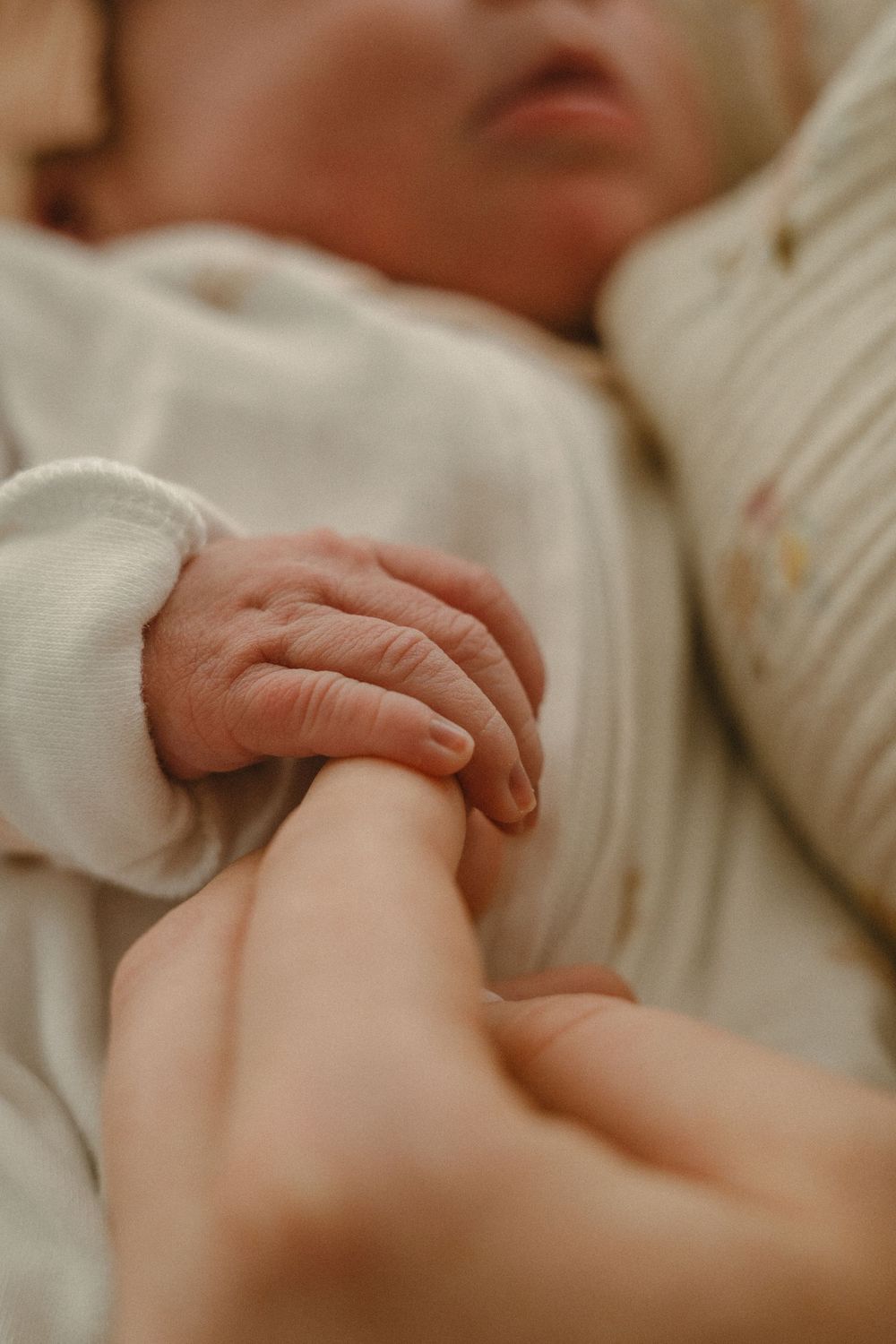 newborn holding moms finger