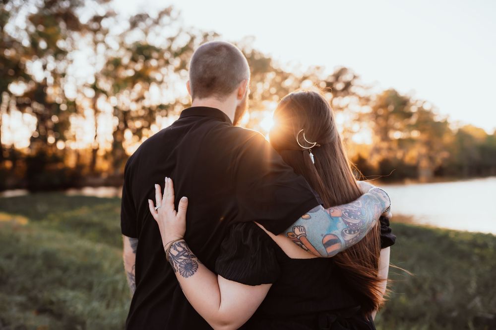 engaged couple looking at sunset over the water, golden hour
