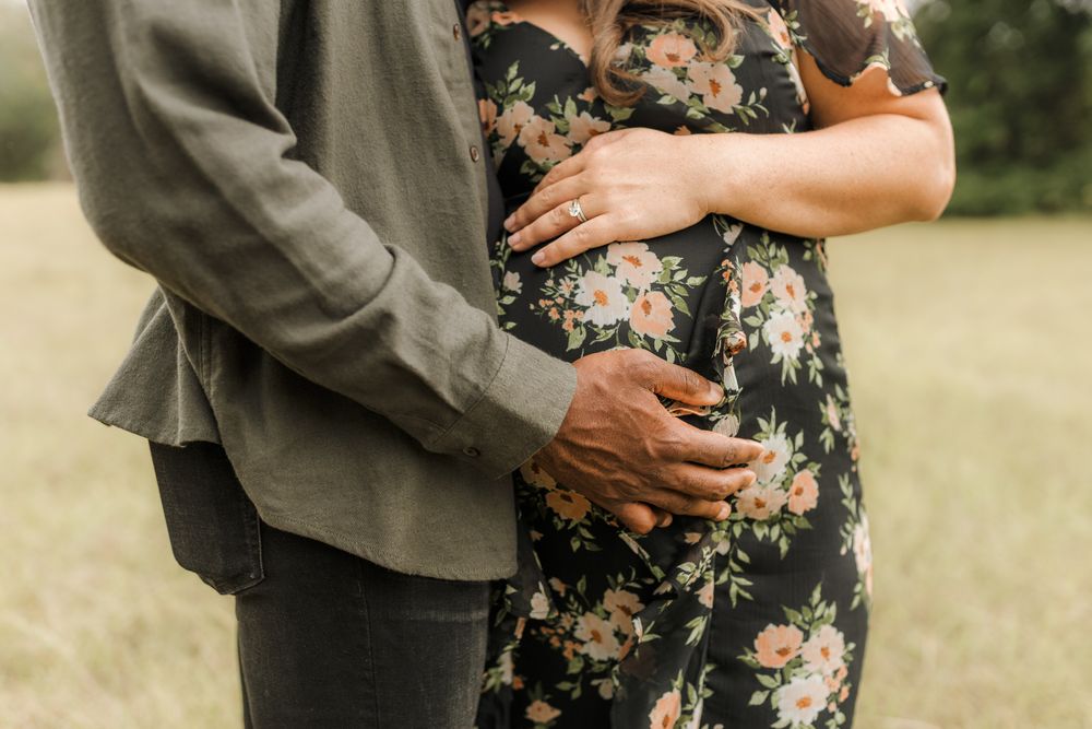 Close-up detail shots of couple holding hands and embracing in a floral dress and olive jacket outdoors.