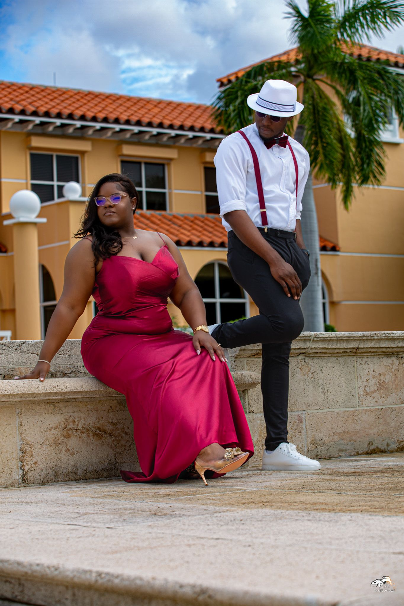 Couple in vintage-inspired outfit poses on Spanish-style building steps.