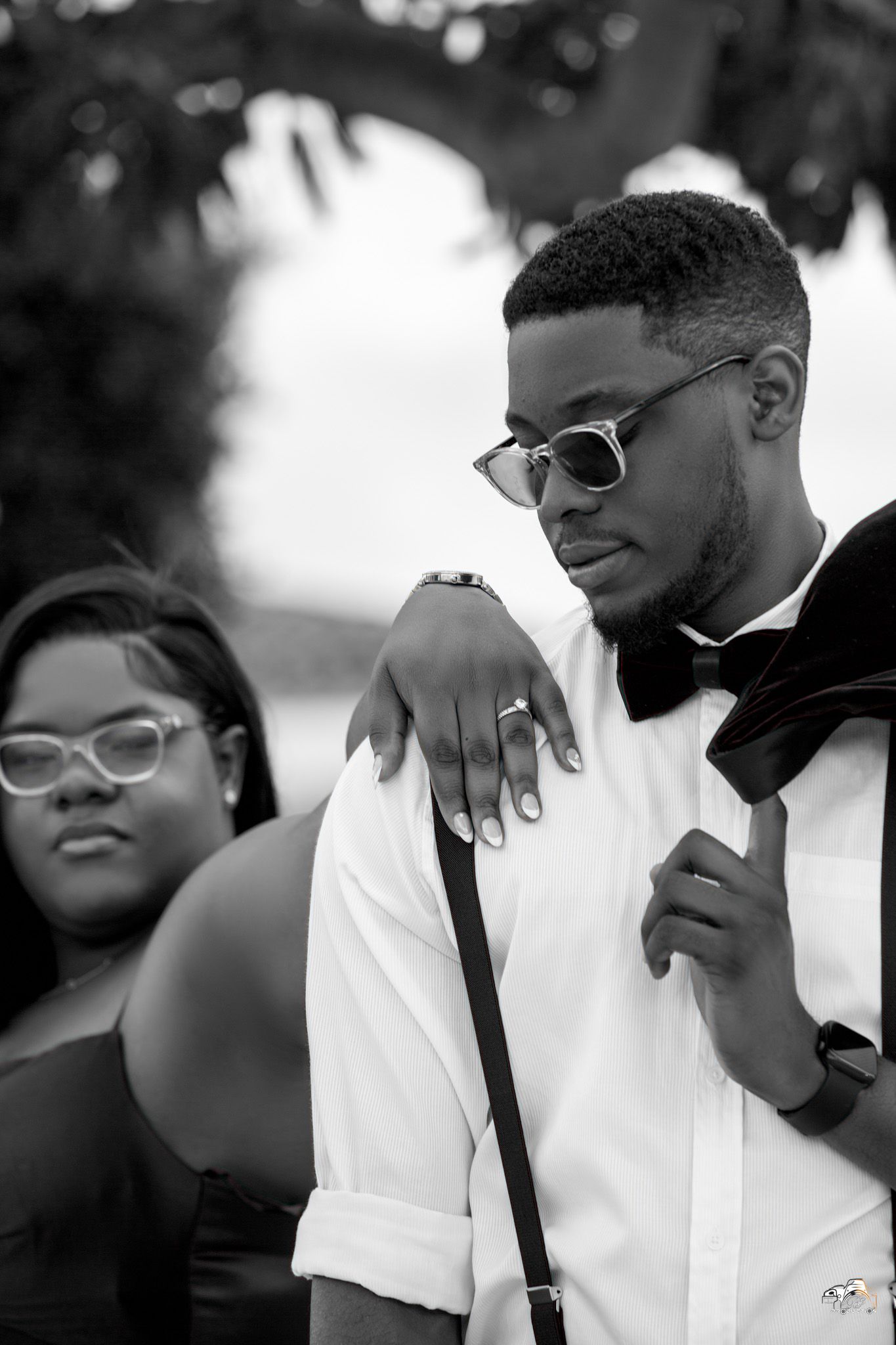 Stylish black and white portrait of couple in formal attire with sunglasses.