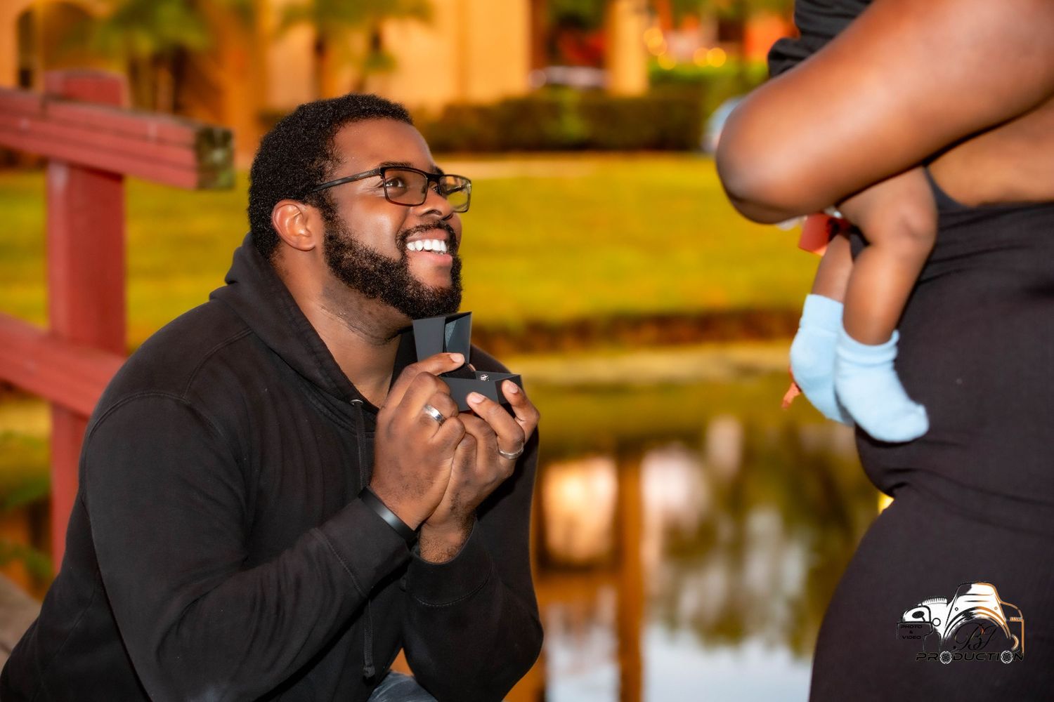Emotional outdoor proposal moment captured with small baby shoes visible in frame.