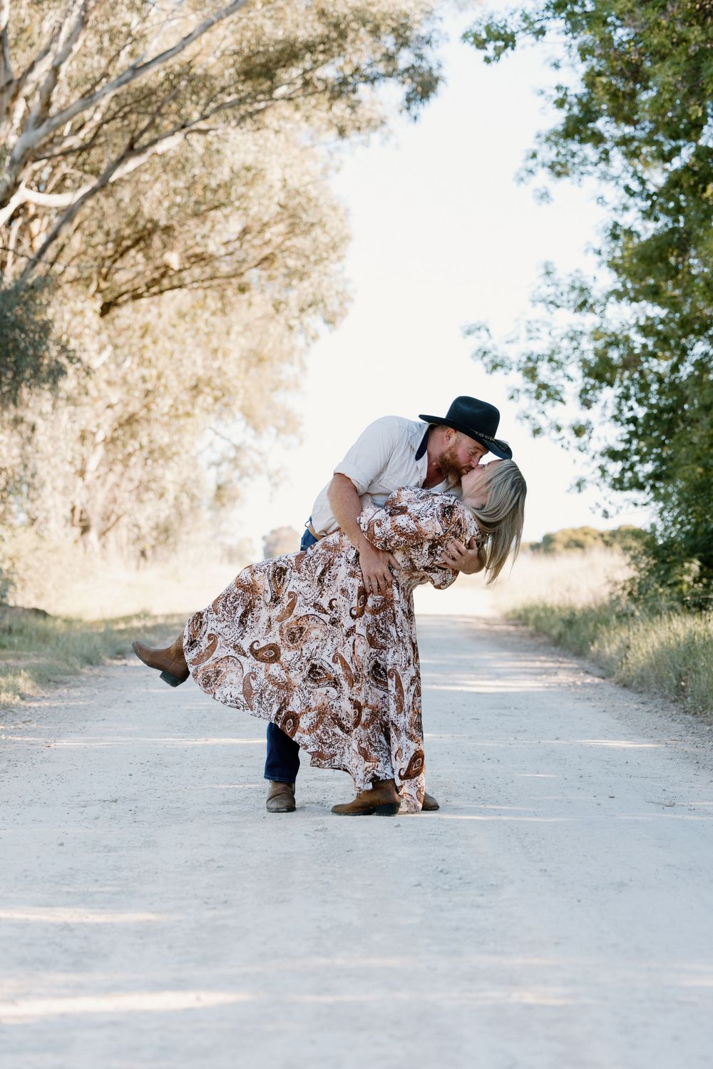 A sequence of four photos showing a person in a floral dress and black hat falling down on a dirt path.