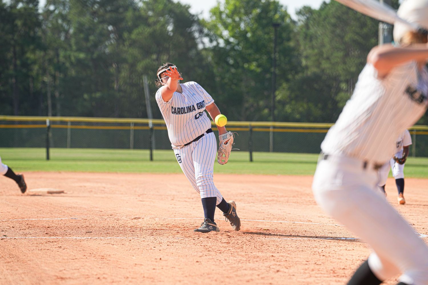 Baseball pitcher in pinstripe uniform mid-delivery on dirt mound during game.