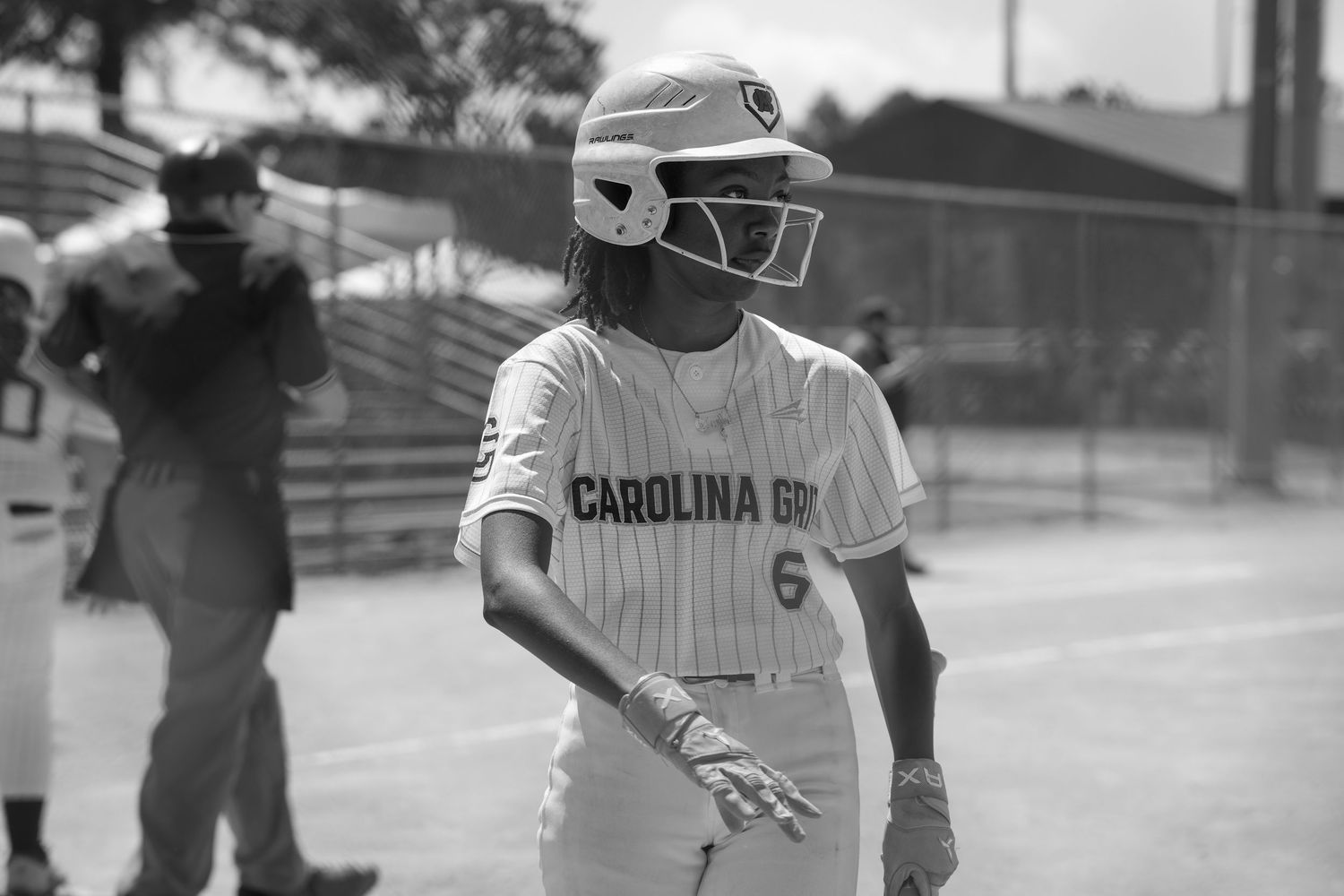 Black and white photo of baseball player in Carolina uniform and protective helmet.