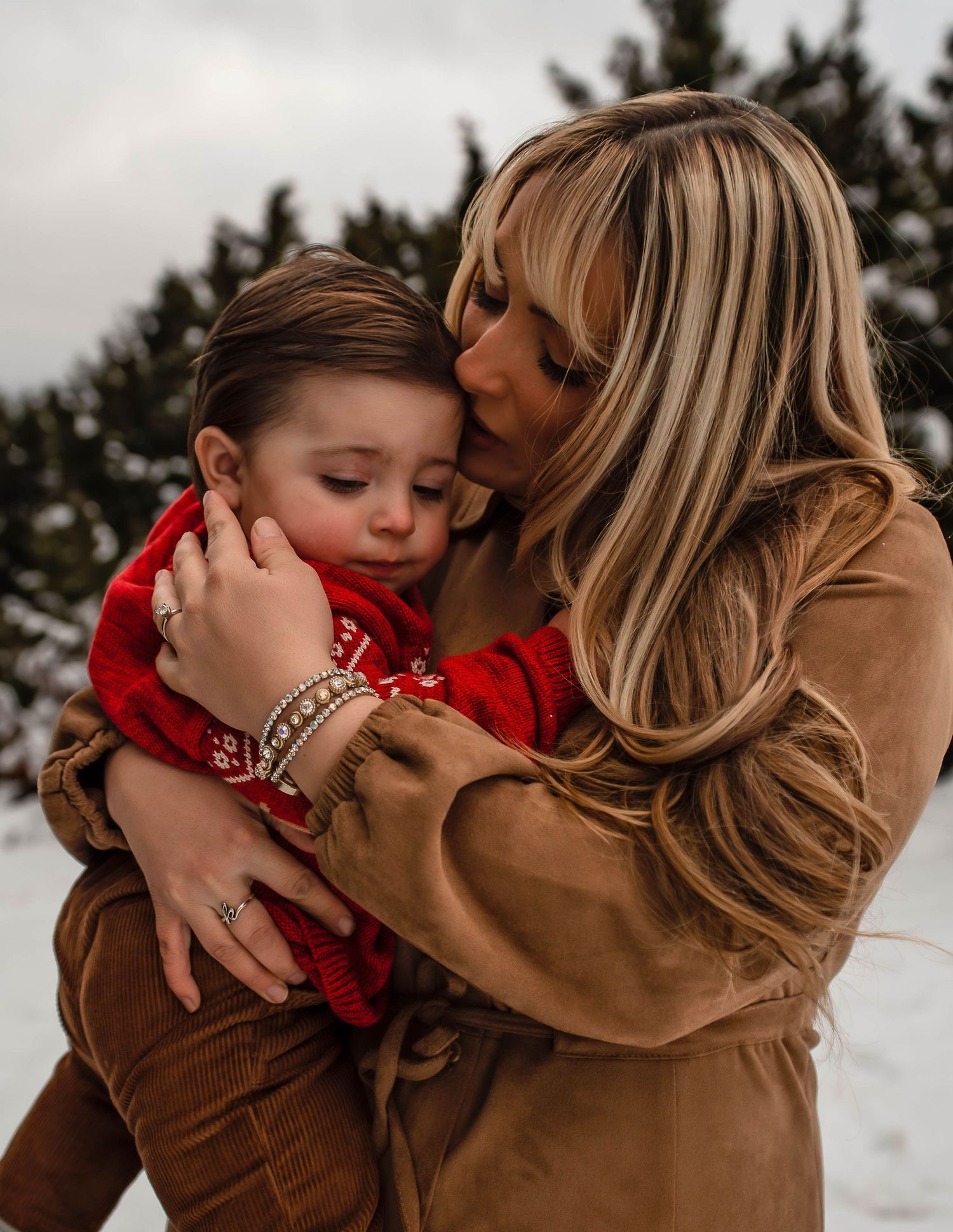 mother holding son giving his a kiss and warming him up from being out in the snow