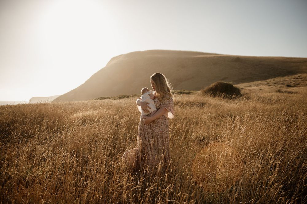A series of soft golden light images shows a couple embracing in a scenic hillside meadow during sunset.