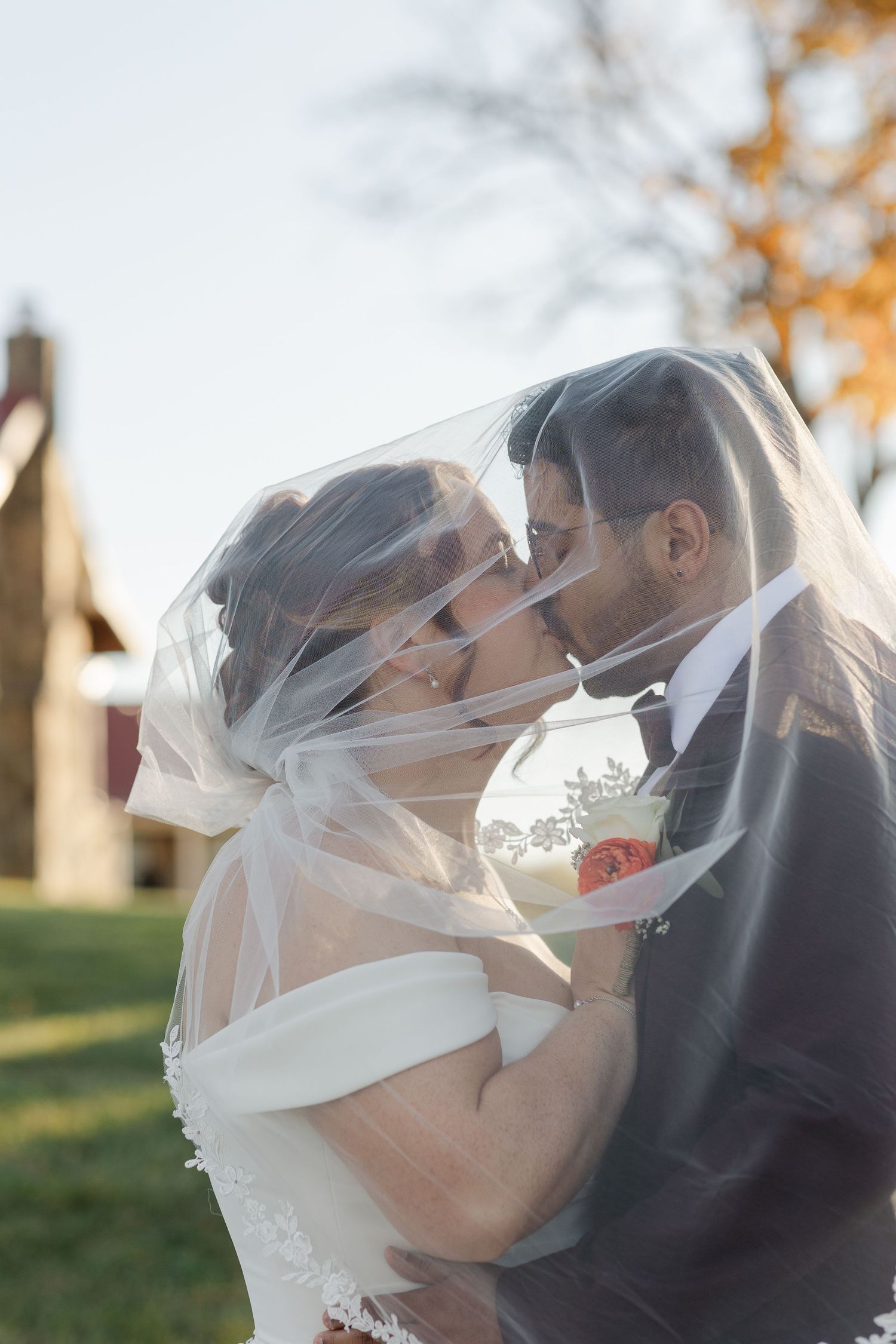 A romantic wedding kiss captured in front of a historic building with distinctive architecture.