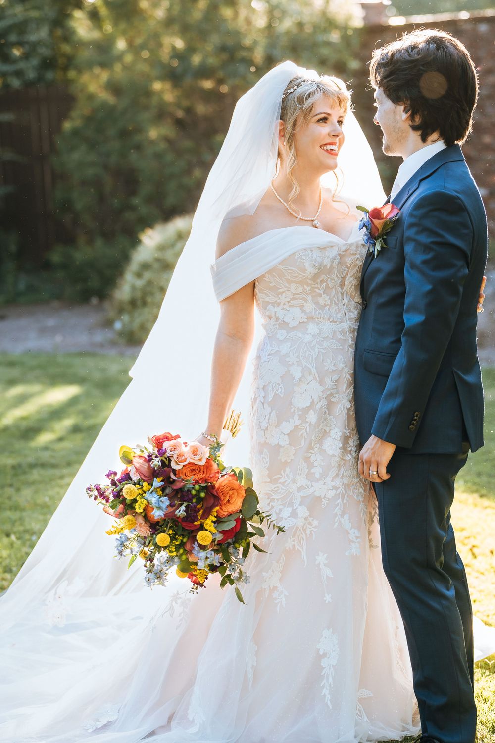 Wedding couple outdoors with colorful autumn bouquet in natural sunlight.
