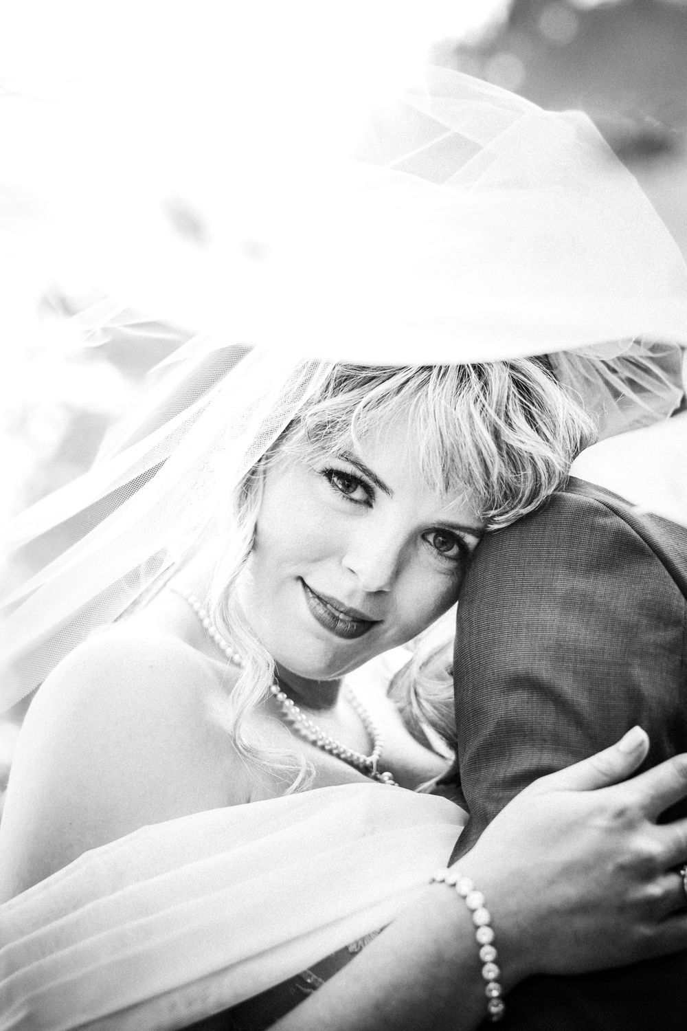 Black and white portrait of a bride wearing a veil and pearl jewelry on her wedding day.
