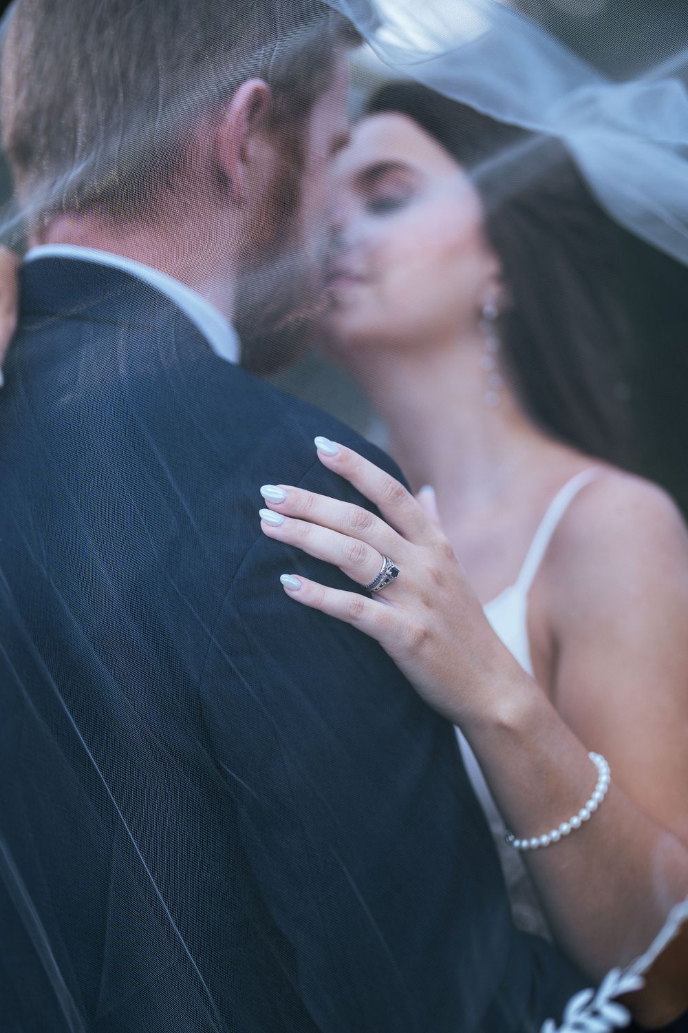 Intimate moment between couple with bride's hand showing engagement ring and bracelet.