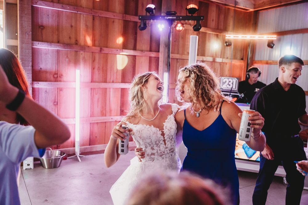 People dancing together in a room with pink lighting and wooden walls during a social gathering.