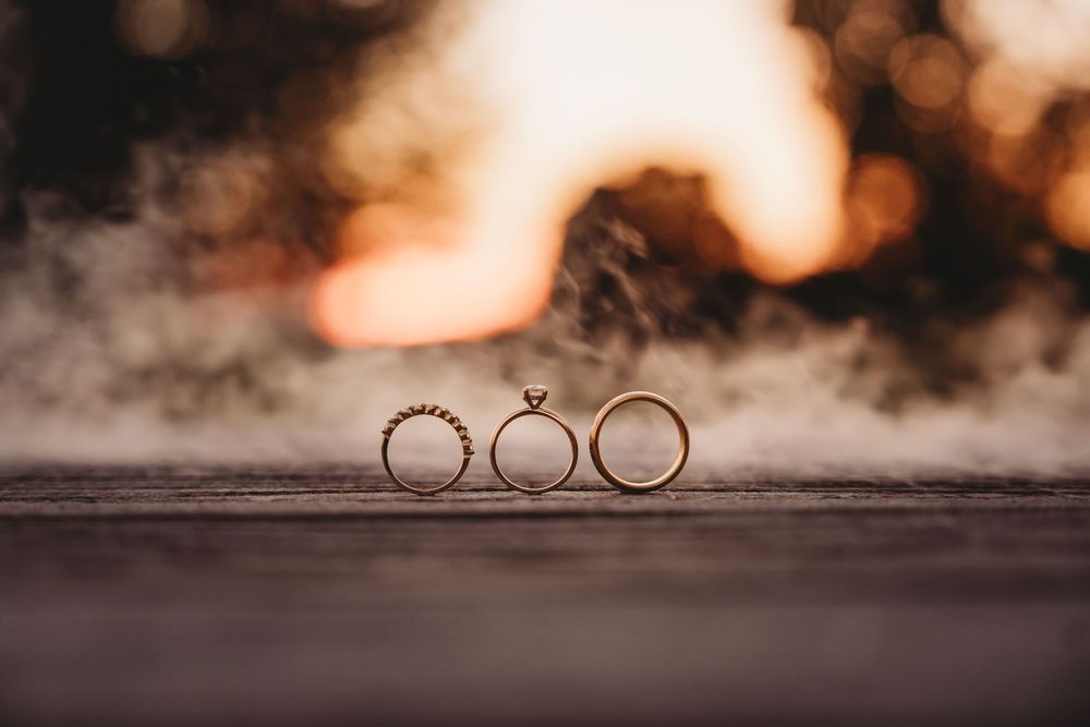Three wedding rings artistically arranged on a dark textured surface.