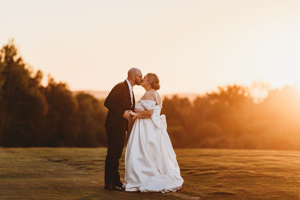 Romantic sunset portraits of newlyweds embracing in golden evening light.