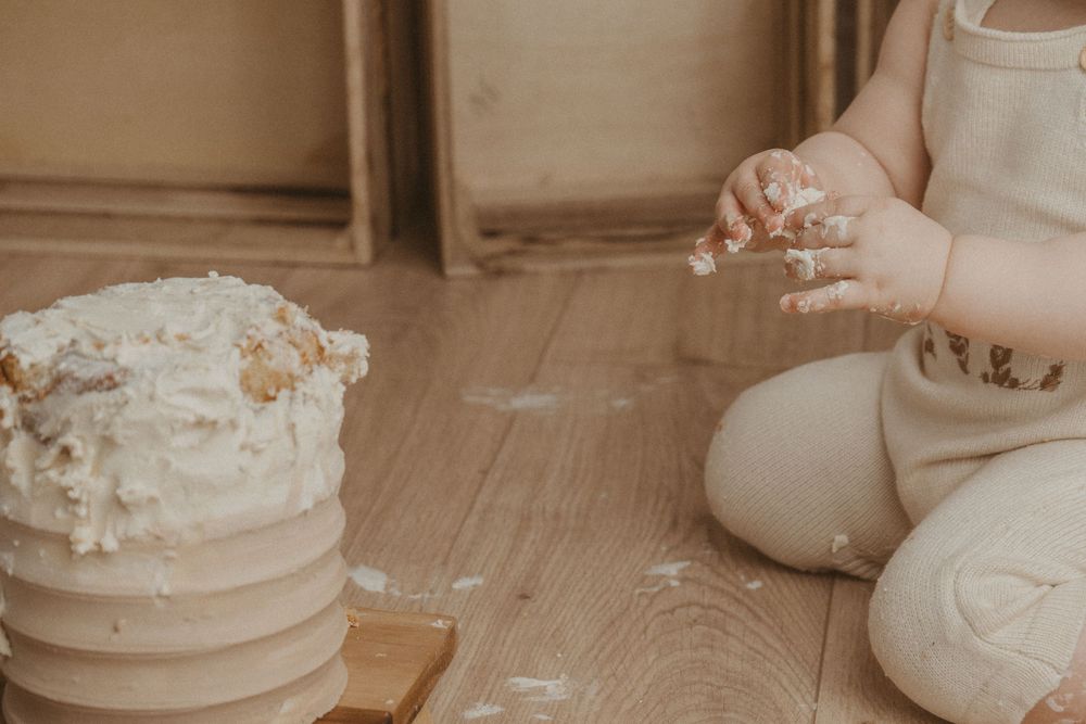 A rustic wedding cake sits on a wooden surface with delicate white frosting and floral decorations.