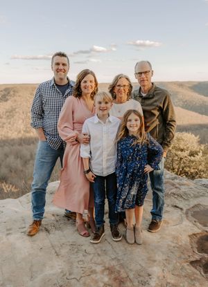 Multi-generation family portrait on mountain overlook during golden hour.
