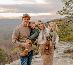 A family shares smiles while posing together on a scenic mountain vista.