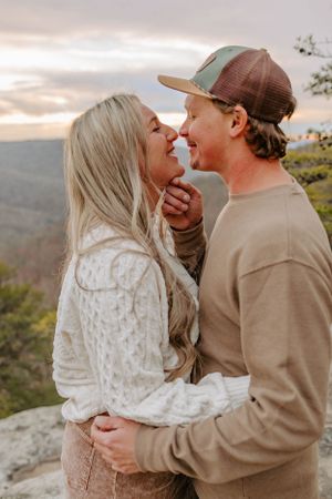 A couple shares an intimate moment on a mountain overlook during sunset.