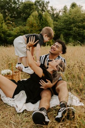 A family plays together on a picnic blanket in a golden summer field.