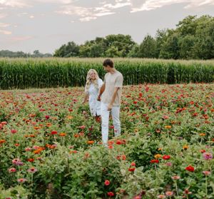 A couple stands intimately among red poppies with cornfields in the background.