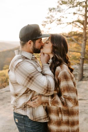 A tender embrace shared on a mountain cliff during golden hour.