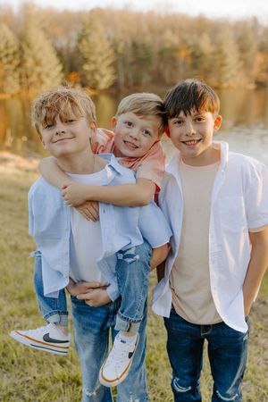 Three brothers sharing a playful moment together outdoors during golden hour.