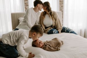 A cozy family moment captured on a white sofa with a baby and sibling.