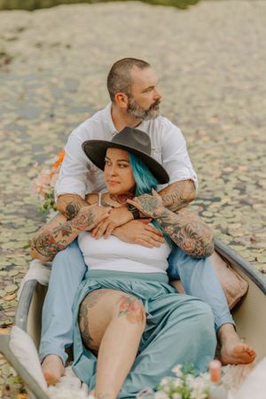 Couple relaxing in canoe with tattoos and teal hair.