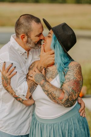 Intimate moment between couple with tattoos and teal hair.