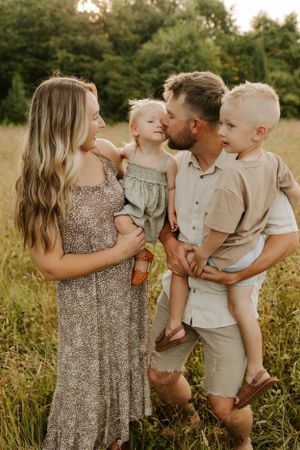 Family shares tender moment in sunlit field during golden hour.