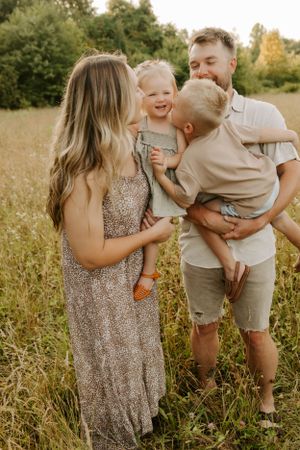 Happy family sharing tender moments together in a sunlit meadow during golden hour.