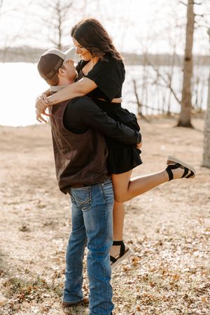 Playful engagement photo of couple embracing by winter lake.