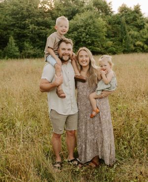 Family of four poses together in a golden field during summer.