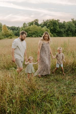 Family walking together through tall grass in a sunlit meadow.