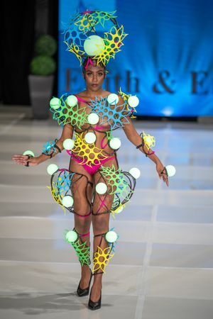Avant-garde fashion runway look featuring illuminated geometric shapes and colorful patterns with glowing orbs on the catwalk.