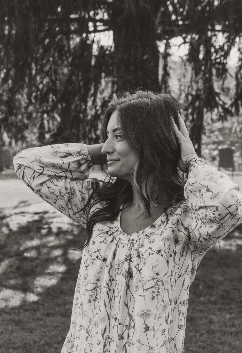 A series of black and white photos showing someone in a floral patterned dress posing expressively in a forest setting.