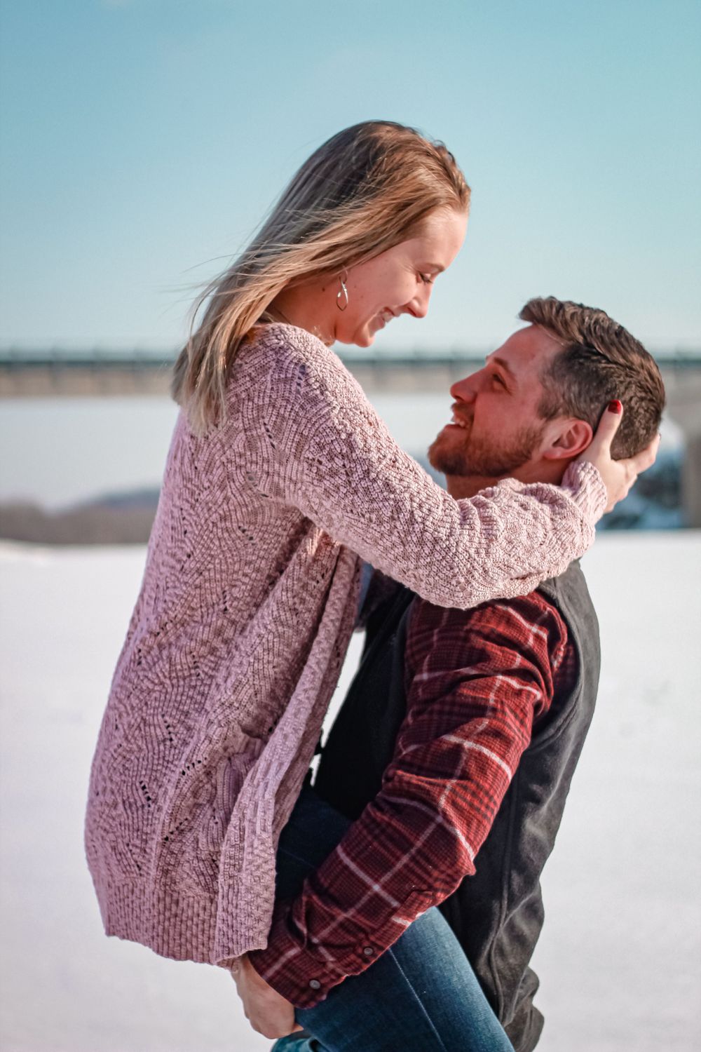 Couple sharing a romantic moment in the snow while wearing cozy winter clothing.