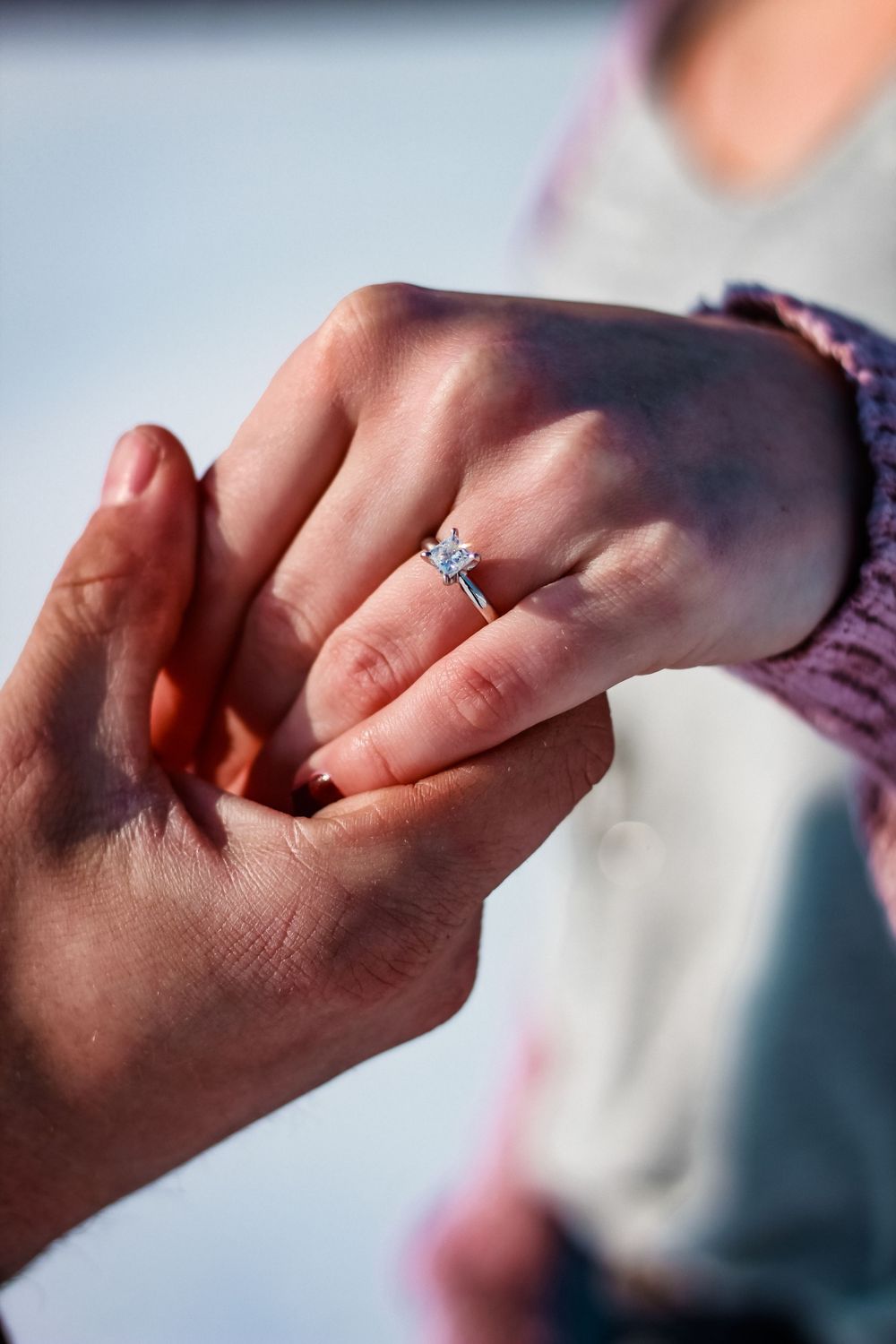 Close-up of diamond engagement ring being placed on finger.