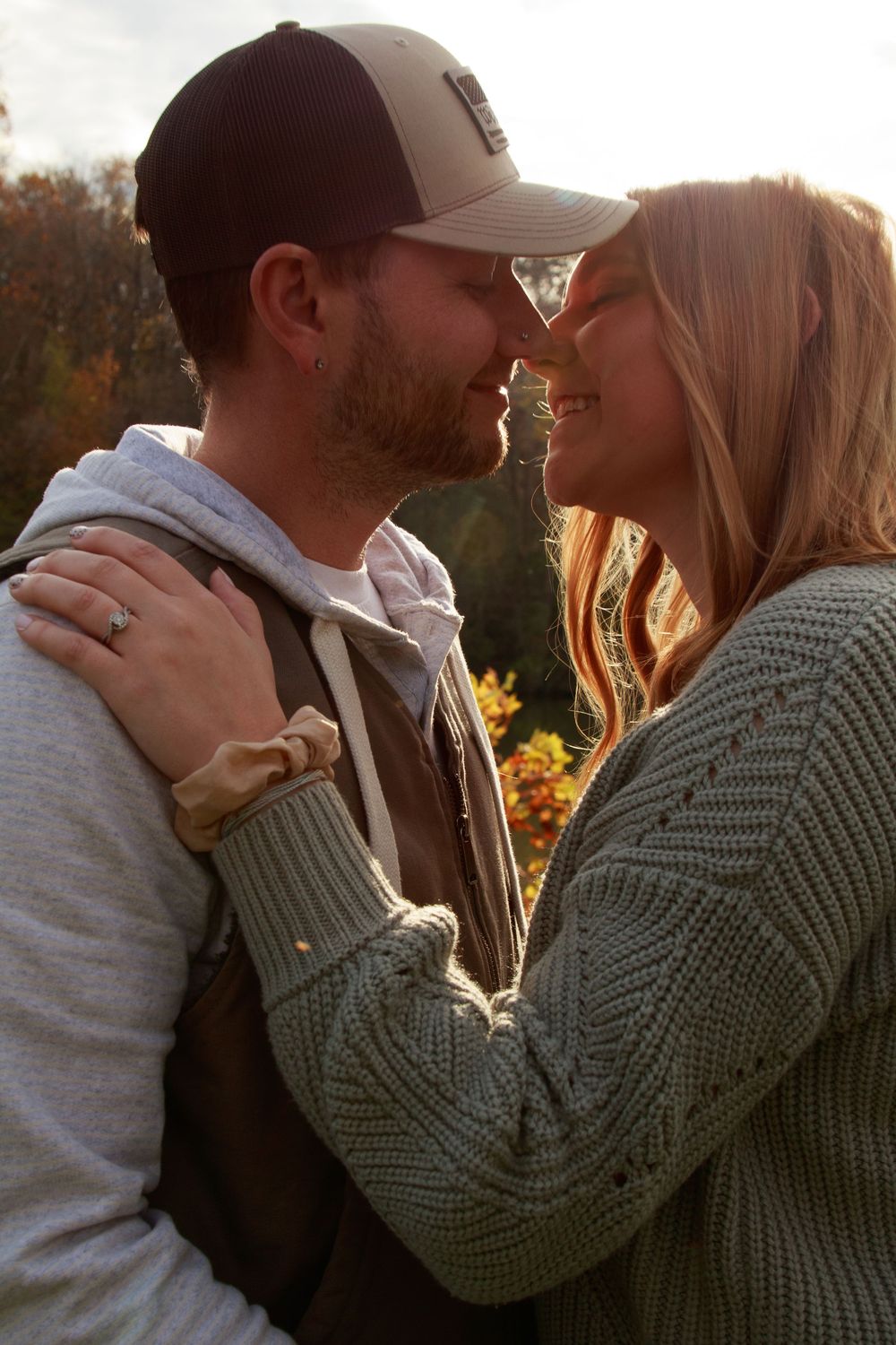 Romantic couple embracing in warm sunset light wearing knit sweater and casual attire.