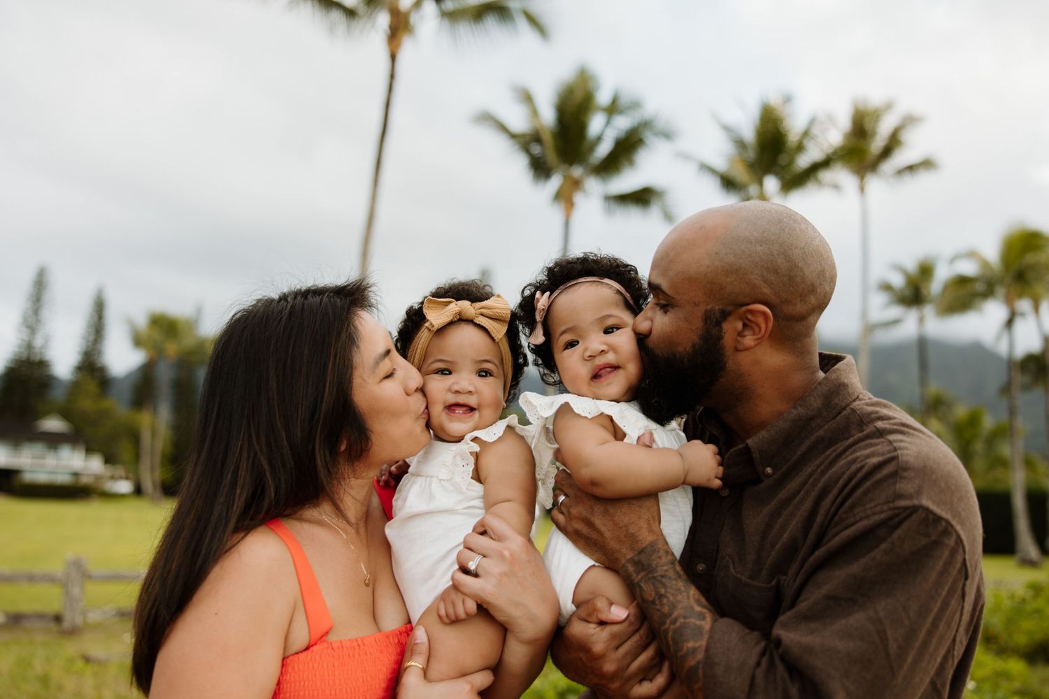 A happy family moment captured outdoors with palm trees in the background in Hawaii.