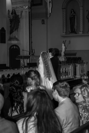 Black and white photo of a bride and groom at the altar during a Catholic church wedding ceremony.