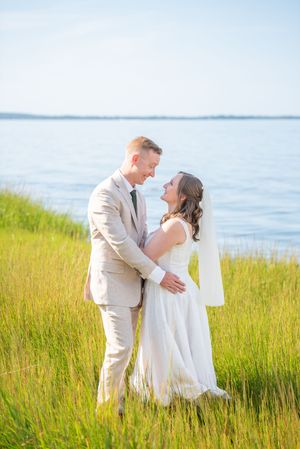 Romantic wedding portraits in tall coastal grass with ocean views and soft natural lighting.