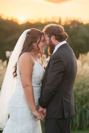 An intimate sunset wedding portrait with golden light and tall grass in the background.