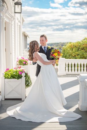 A joyful wedding dance on a sunny white veranda with colorful flowers.