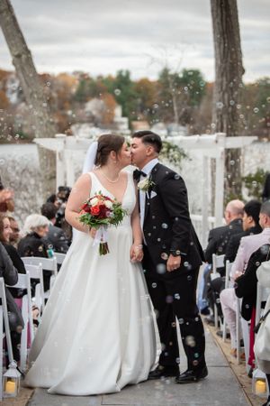 Winter wedding ceremony outdoors with snow falling and white chairs lined up for guests.